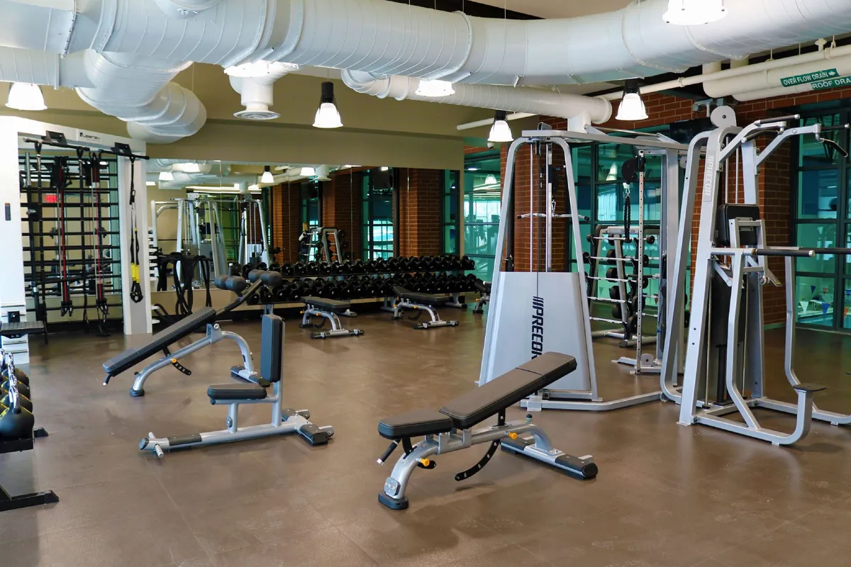 A vibrant fitness area equipped with weightlifting benches, dumbbell racks, and various exercise machines. The space is energetic, well-lit, and ready for personal or group workouts, hinting at year-round recreational opportunities.
