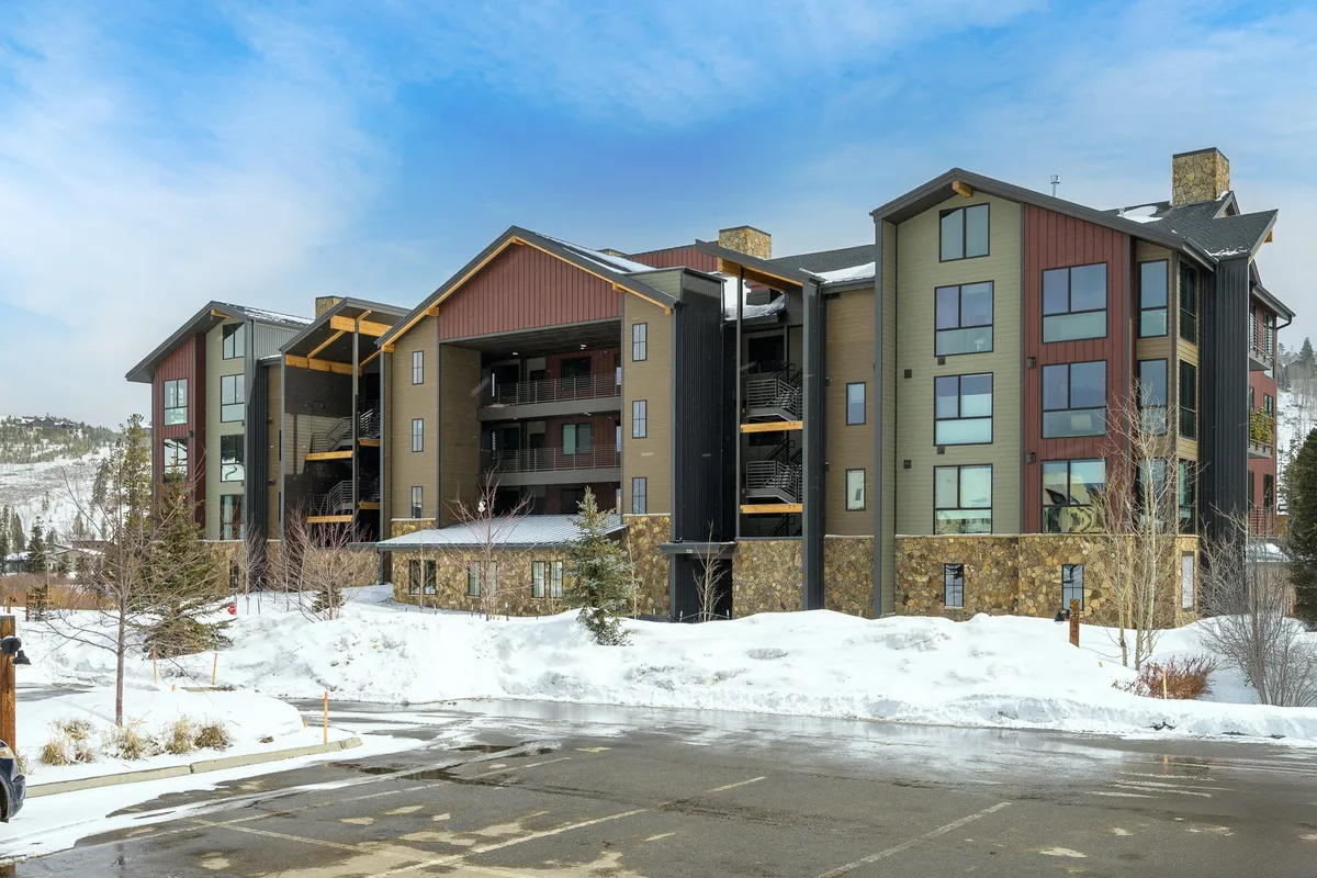 A welcoming view of the condo’s modern exterior set against a snow-covered mountain landscape. The stone accents and balcony hint at cozy evenings and direct access to nature’s playground, while the snow scene emphasizes the proximity to winter sports.