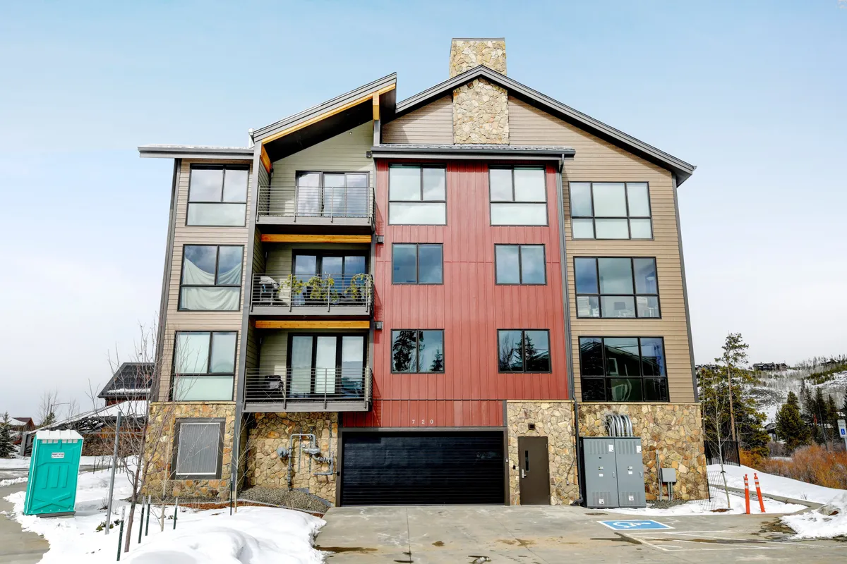 A contemporary exterior shot of the condo building, showcasing modern architecture with large windows and plant-lined balconies. A touch of snow hints at year-round outdoor possibilities, while the inviting facade suggests a welcoming environment for families.