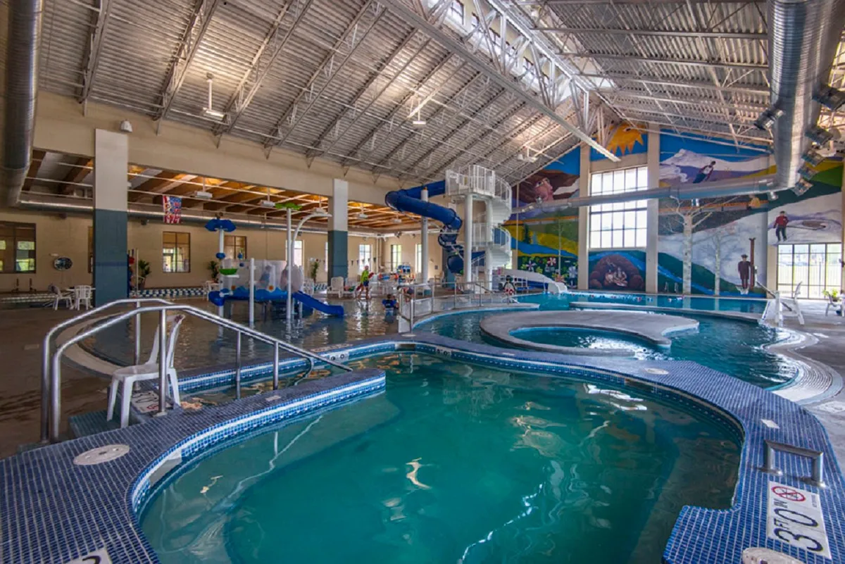 An indoor scene featuring a lively play area with a swimming pool, water slide, and children happily playing. The space is vibrant and designed for kids’ enjoyment, echoing the emphasis on family amenities and child-friendly comforts.